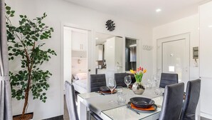 A modern dining area with a glass table, black chairs, and a vase of tulips. - Beach front home in Peroj with house sea view (Peroj)