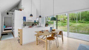 A modern kitchen with a large island, white cabinetry, and a view of a lush garden through large windows. - Awesome home in Fårevejle with kitchen (Fårevejle)