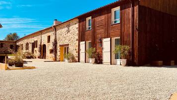 Un bâtiment doté d’une cour en gravier, d’une façade en bois et de plusieurs portes.