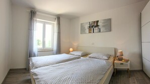 Un lit double avec une couvre-lit à motifs, deux lampes de chevet, une petite table de chevet et une fenêtre avec des rideaux.