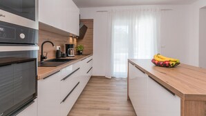 Eine moderne Küche mit Einbauofen, Kaffeemaschine und einer Obstschale auf der Arbeitsplatte.