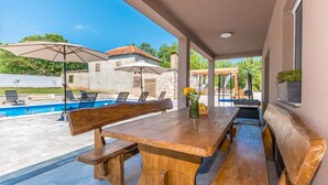 Eine Terrasse im Freien mit Pool, Holzliegen und Sonnenschirmen.