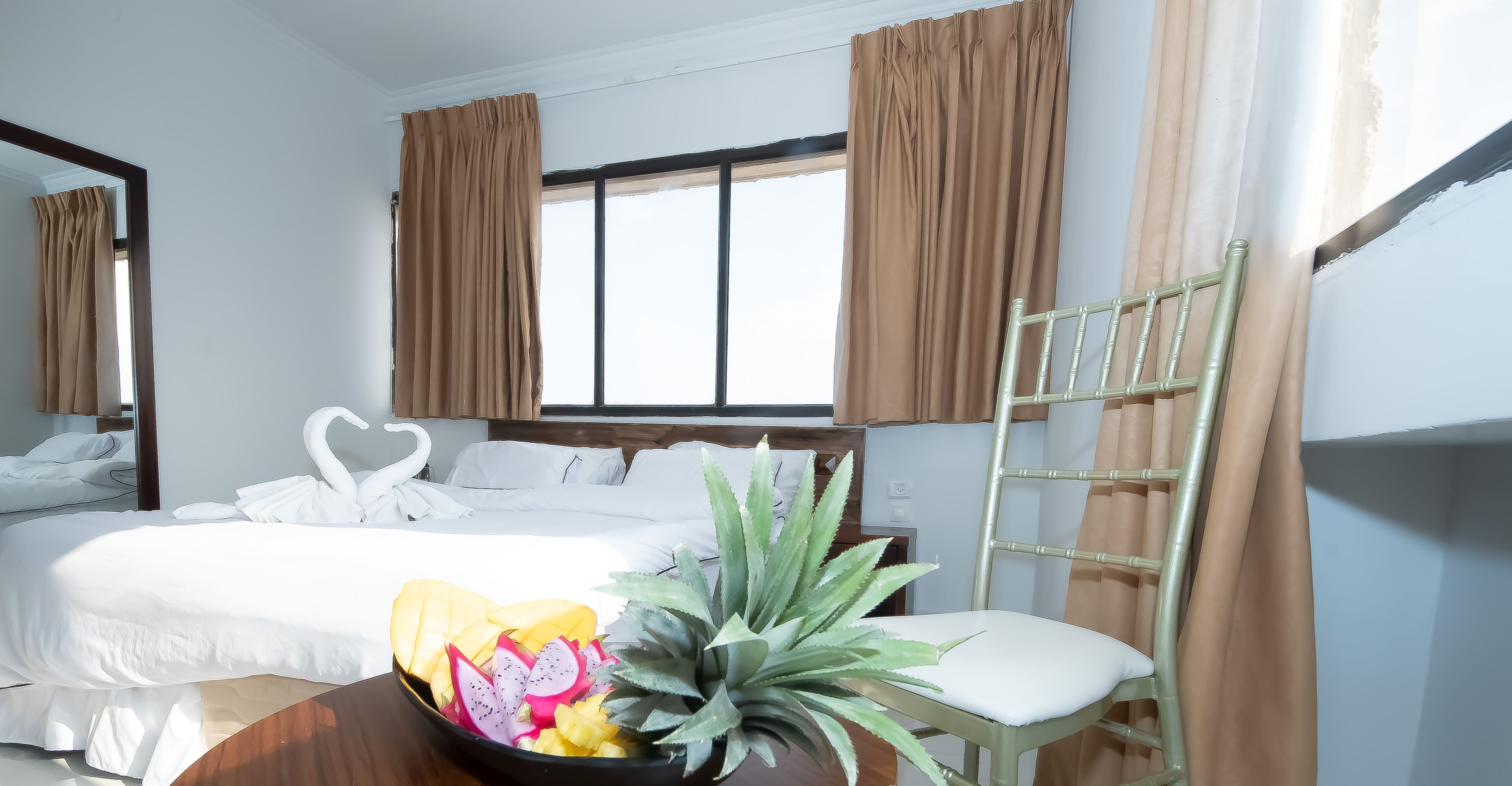 Una habitación de hotel con una cama, una silla, una planta y un frutero.