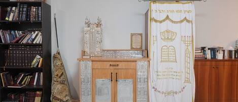 A study room with a bookshelf, a cabinet, and a Torah scroll.