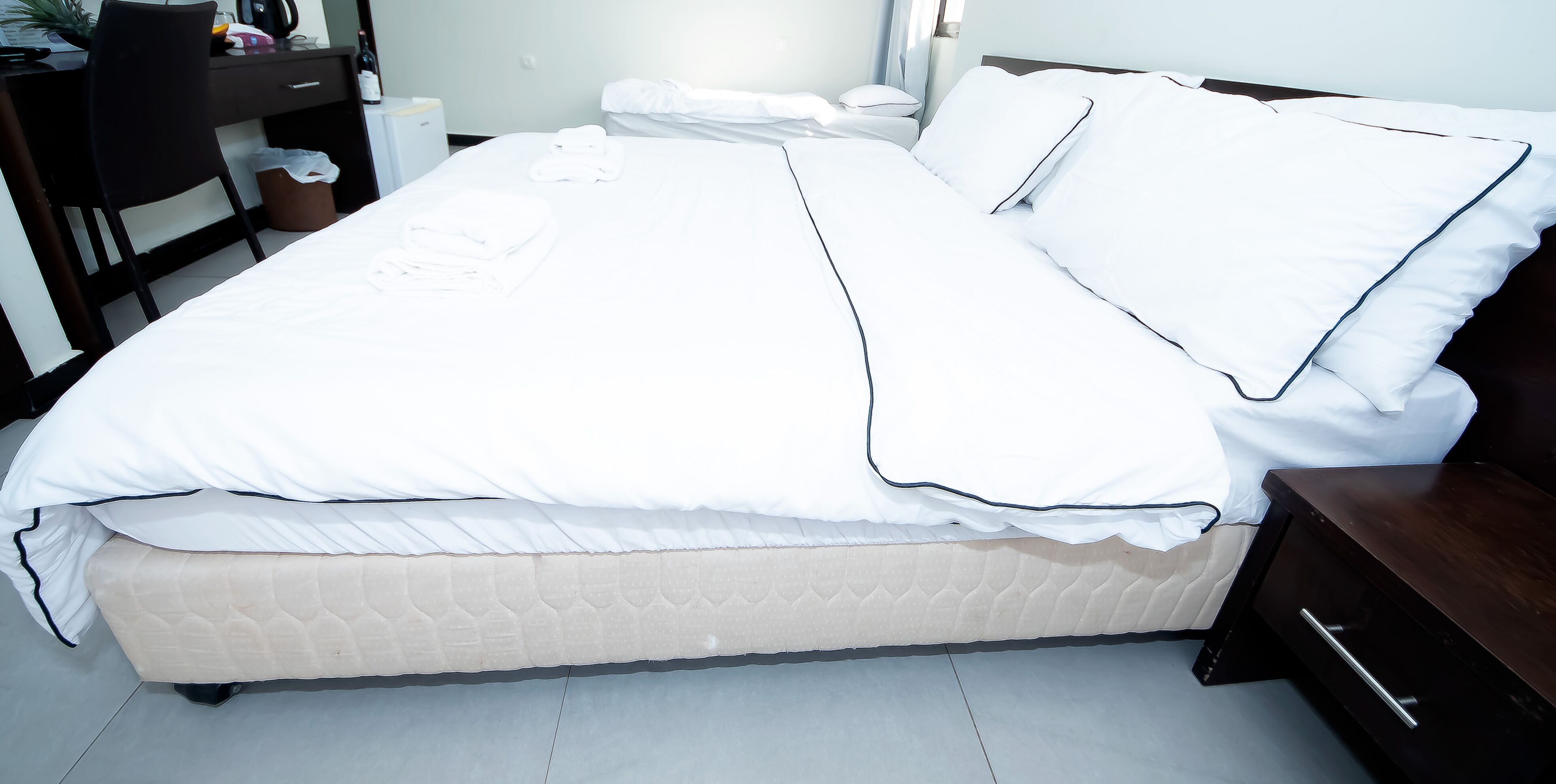 A neatly made bed with white bedding and a dark wooden headboard.