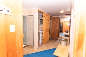 Ein Flur mit Holztüren, ein Badezimmer mit Waschbecken und Spiegel, und eine blaue Matte auf dem Boden.