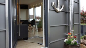 Un interior moderno con una zona de comedor, una gran decoración con forma de ancla y una planta en maceta con flores.