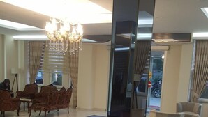 A modern lobby with purple armchairs, a chandelier, and a large mirror. - Engin Hotel (Gallipoli)
