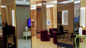 A modern lobby with a reception desk, seating area, and a TV screen. - Engin Hotel (Gallipoli)