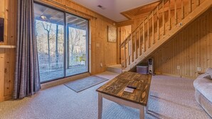 A wooden interior with a large sliding glass door, a staircase, and a wooden table. - Beautiful Lake Front Log Cabin with Dock  (Mill Spring)