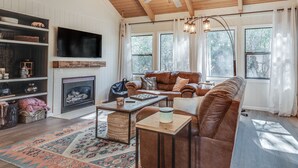 A cozy living room with a fireplace, leather sofas, a coffee table, and a television.