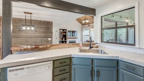 A modern kitchen with a large island, built-in appliances, and a large window providing natural light.