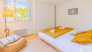 A bedroom with a bed, a chair, a window, and a radiator. - Le Poisson Bleu - by Winkyhouse (Cassis)