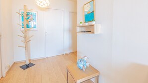 A hallway with a coat rack, a door, a small table with a decorative item, and a wall-mounted shelf with a picture. - Le Poisson Bleu - by Winkyhouse (Cassis)