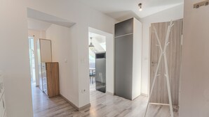 A modern interior with a wooden floor, a grey wall, and a white door.