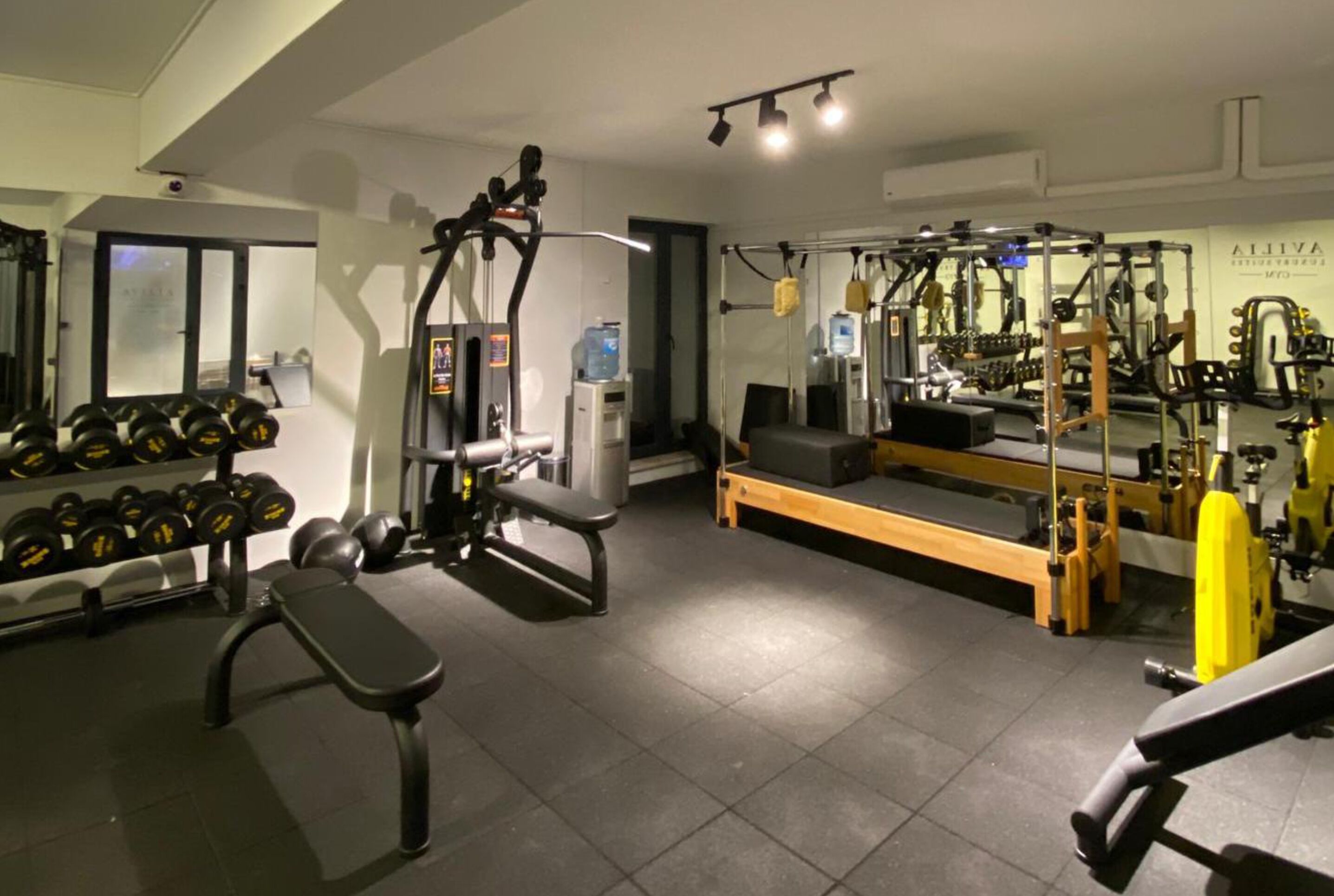 A gym with various exercise equipment, including dumbbells, a bench, and weight machines.