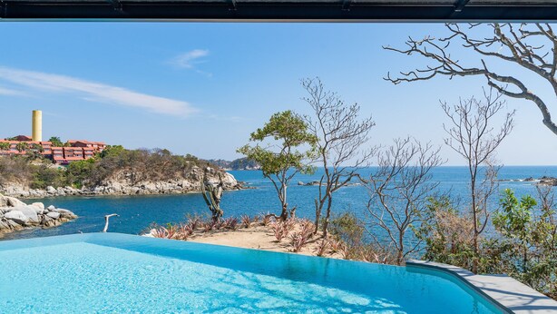 A clear blue pool with a view of the sea and rocky coastline. - Eco-Friendly Oceanfront Penthouse W/ Beach Access (Huatulco)