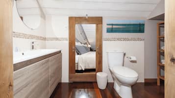 Une salle de bain avec un meuble-lavabo en bois, des toilettes et un miroir.