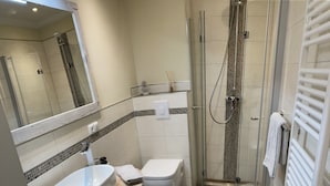 Een moderne badkamer met een douchecabine van glas, een wit wastafelmeubel en een toilet.