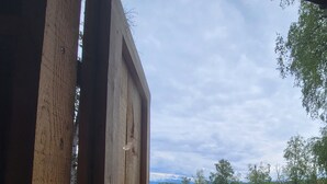 A view from a window overlooking a construction site with a lake and forest in the background. - Vintage Trailer with  access to Big Lake & Private Campground  (Big Lake)