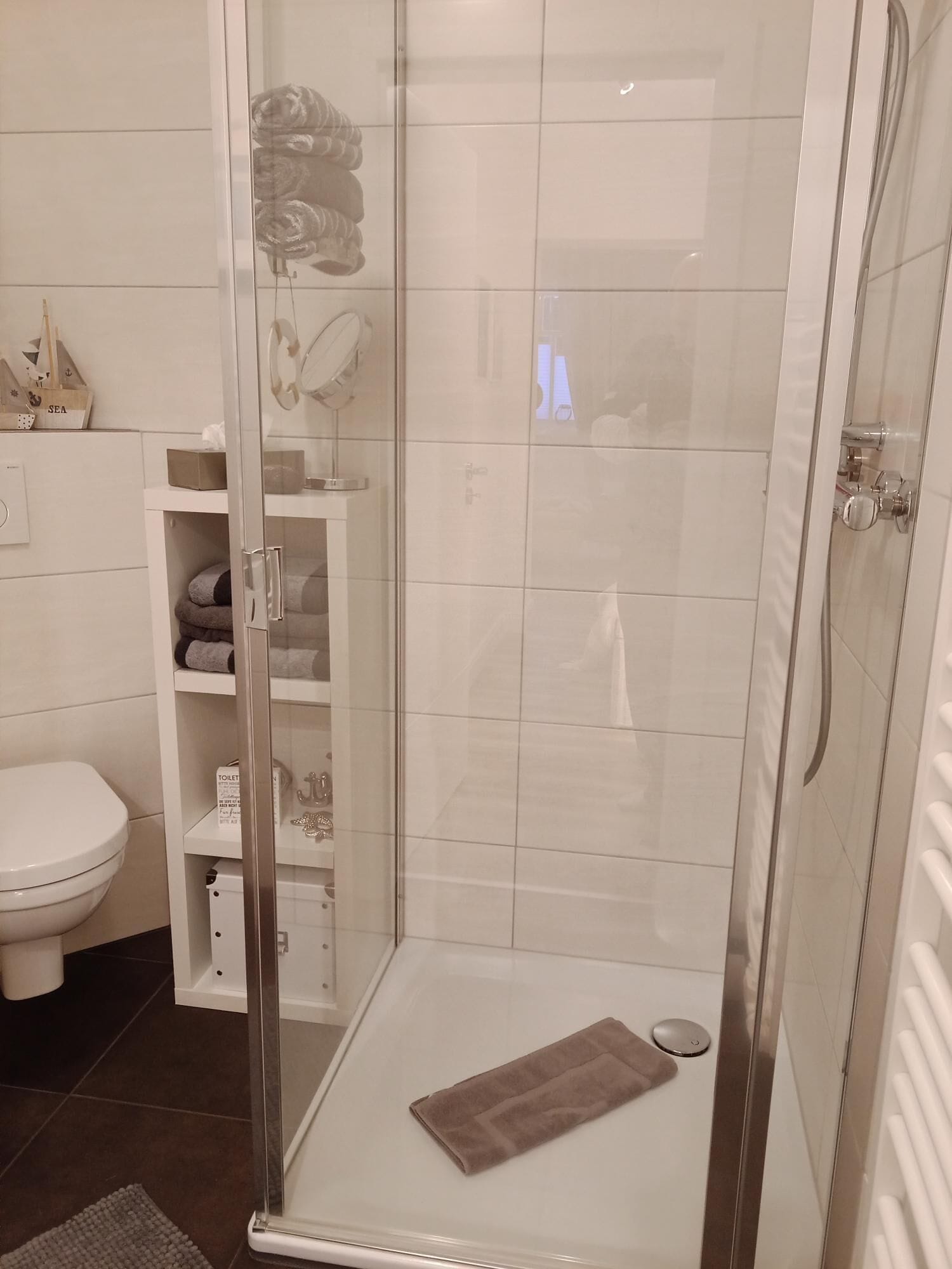 Une salle de bain moderne avec une douche à parois de verre, des toilettes et un porte-serviettes.