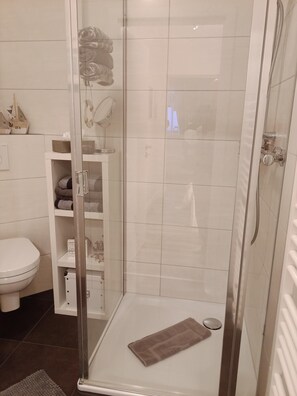 Un baño moderno con cabina de ducha de vidrio, inodoro y barra para toallas.