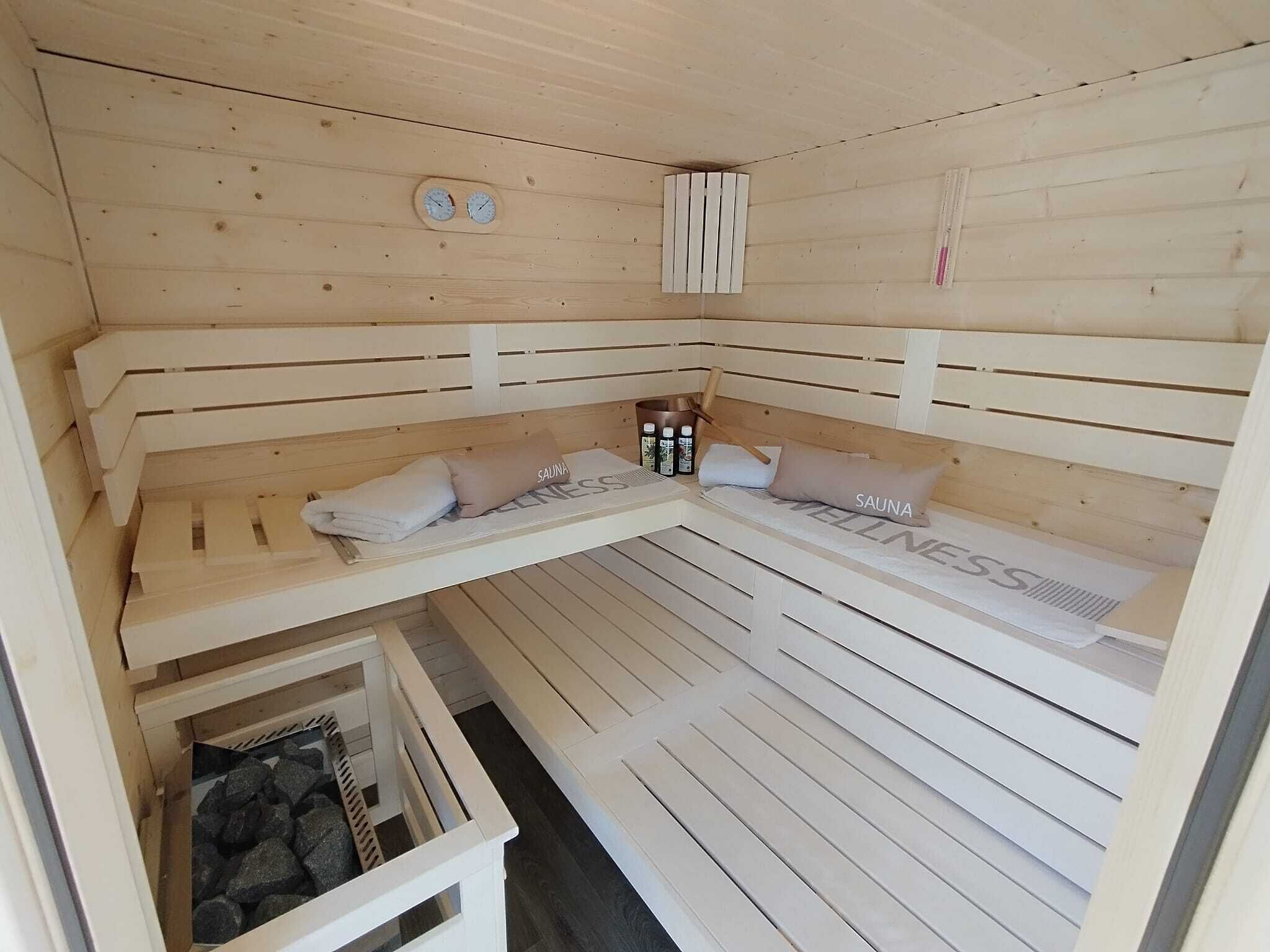 Een sauna met houten banken, handdoeken en waterflesjes.