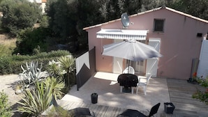 Een patio met een tafel en stoelen, een overdekte zithoek en een schotelantenne op een gebouw.