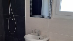 Een badkamer met een witte wastafel, toilet en douche.