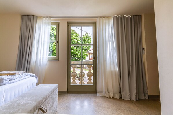 A room with a bed, a bench, a window with curtains, and a balcony with a railing. - Romantic Private Villa with Pool and Stunning Views (Kostanjevica na Krasu)
