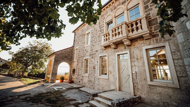 Un edificio de piedra con un arco central, varias ventanas y un balcón.