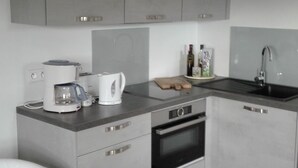 Eine moderne K üche mit grauen Schränken, einem Einbauofen, einer Kaffeemaschine und einem Spülbecken.