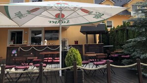 Un espace extérieur aménagé avec des tables et des chaises, un parasol et un bâtiment en arrière-plan.