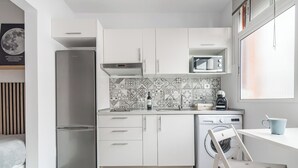 A compact kitchen with white cabinets, a stainless steel refrigerator, a microwave, and a washing machine. - Minimalist Studio 3 Minutes Walk to Las Canteras Beach (Las Palmas de Gran Canaria)