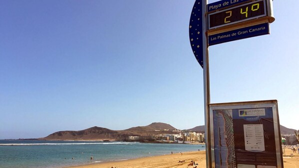 A beach scene with a digital sign displaying the time.