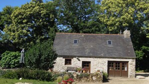 A stone house with a sloped roof, two windows, and a wooden door.