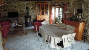 A cozy living room with a stone wall, a fireplace, a television, and a dining area with a table and chairs.