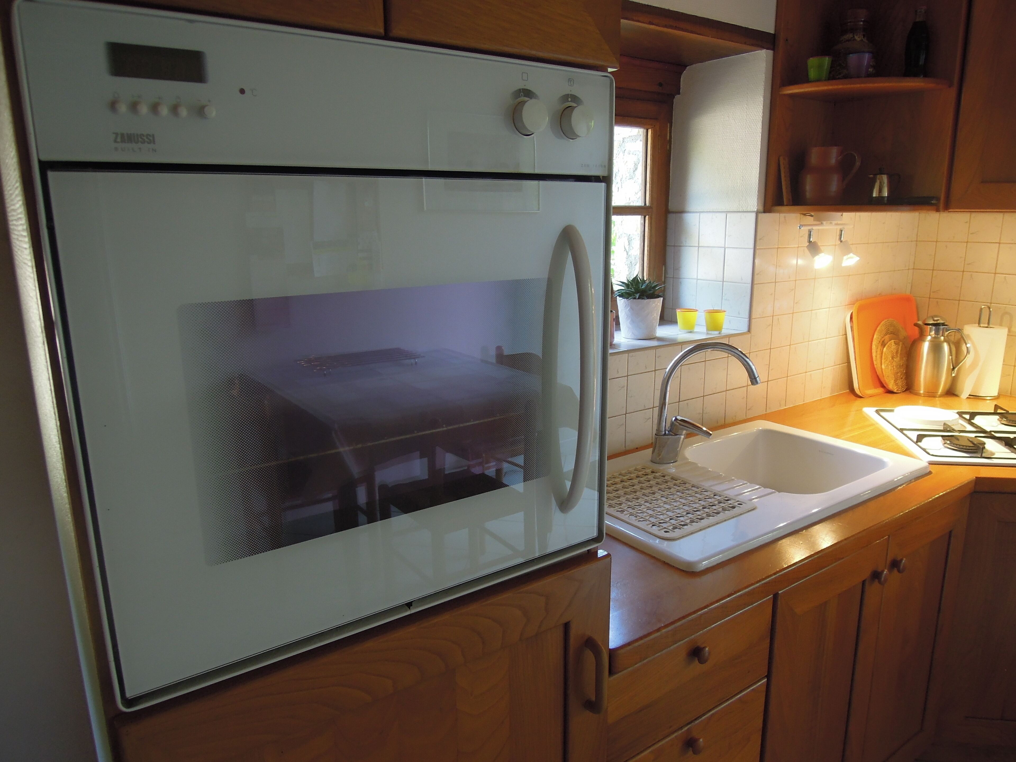 A kitchen with a built-in oven, a sink, and wooden cabinets.