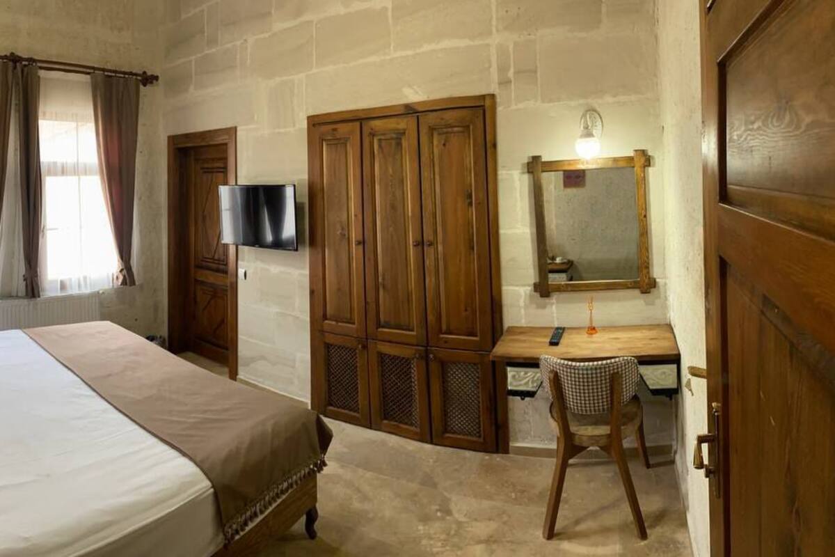 Un dormitorio con una cama grande, un escritorio con silla, un televisor y un espejo.