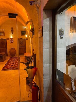 A warmly lit interior with a reception desk, a fire extinguisher, and a traditional rug.