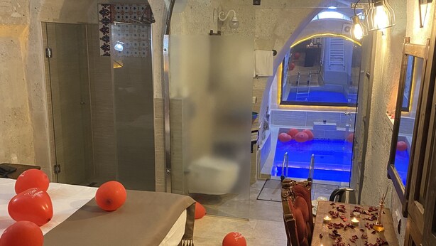 A room with a bed, a table with candles, and a view of a pool. - Zuwinasa House Hotel (Avanos)