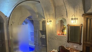 A cozy room with a bed, a table with candles, and a view of a blue-lit area. - Zuwinasa House Hotel (Avanos)