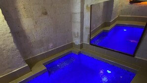 A spa area with a large blue-lit pool and a mirror reflecting the pool. - Zuwinasa House Hotel (Avanos)