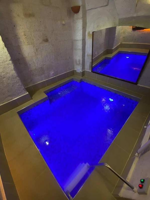 A spa area with a large blue-lit pool and a mirror reflecting the pool. - Zuwinasa House Hotel (Avanos)