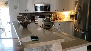 A modern kitchen with white cabinets, stainless steel appliances, and a large island with a built-in sink.