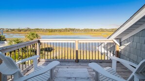 A wooden deck with white chairs and a view of a water body and distant landscape. - Ocean & Wetland views, 3 decks, steps from the beach, 4 BRs, sleeps 10. (Oak Island)