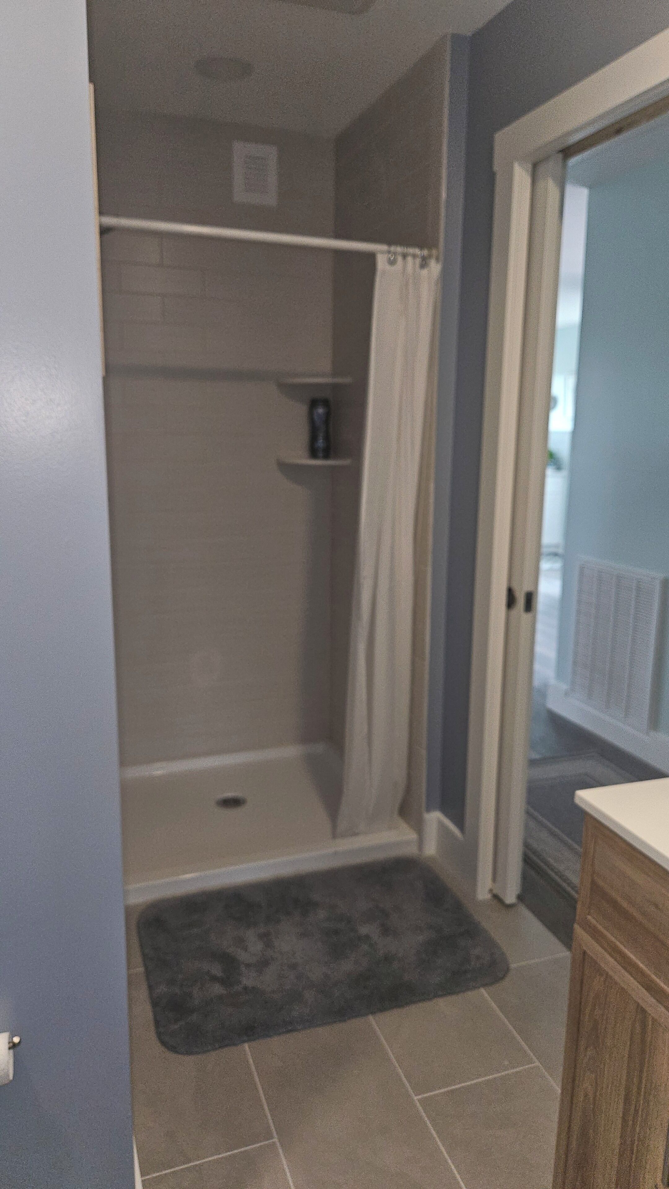 Une salle de bain avec une douche, un porte-serviettes et une petite étagère.
