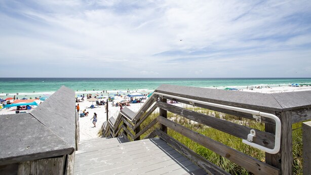A wooden boardwalk leading to a beach with umbrellas and people. - Tradewinds 14 - Updated Gulf-View Condo, Community Pool, Beach Service Included! (Miramar Beach)