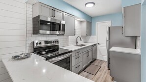 A modern kitchen with white cabinetry, stainless steel appliances, and a marble countertop. - Tradewinds 14 - Updated Gulf-View Condo, Community Pool, Beach Service Included! (Miramar Beach)