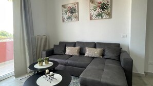 A modern living room with a grey sectional sofa, two side tables, and two floral wall art pieces. - Modern apartment on the Adriatic coast. Only 2 minutes from the beach (Lido Adriano)